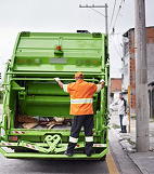 Green waste truck driving through a lane